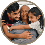 A young boy and girl hugging an older adult, presumably their father or grandfather.
